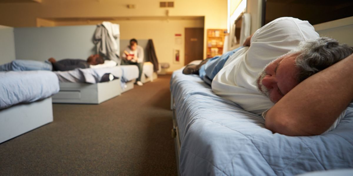 people laying on beds in a homeless shelter